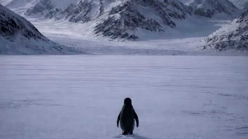 The Nihilist Penguin — a lone penguin walking toward distant mountains across a vast icy landscape